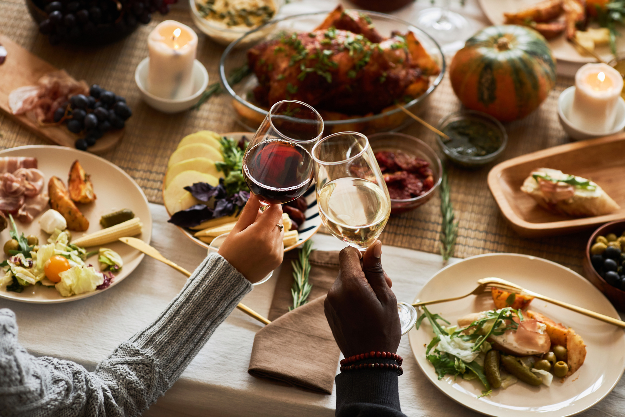 Close up of two people toasting with wine glasses at festive dinner table celebrating Thanksgiving with friends and family, copy space